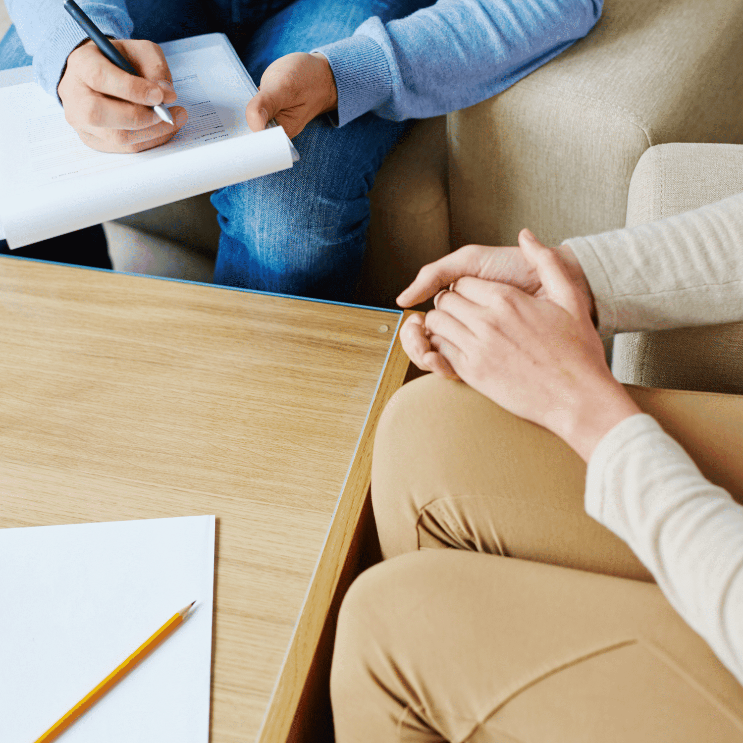 Two people seated at a table, one writing on a clipboard.